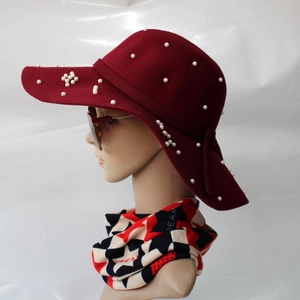 Détail du chapeau en laine bordeaux à large bord avec perles blanches et ruban élégant