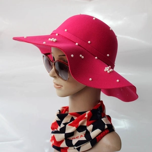 Détail d'un chapeau en laine rose à large bord avec décorations élégantes de perles