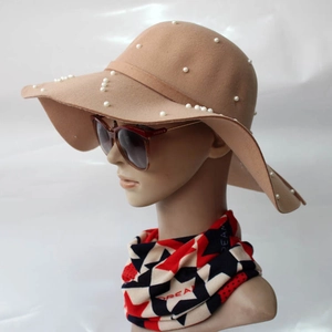 Détail du chapeau en laine camel avec perles blanches élégantes et large bord ondulé