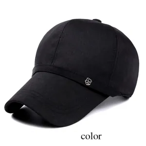 Detail of black cotton baseball cap showing silver metal shield emblem and stitched brim