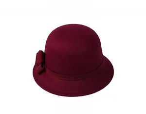 Close-up of wine red wool felt cloche hat with elegant bow detail on white background