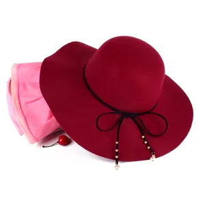 Detail of wine red wool fedora hat featuring black ribbon and pearl bead embellishments