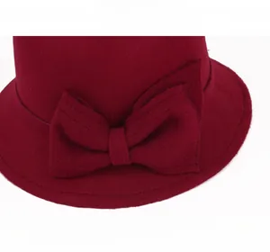 Close-up of a burgundy wool felt cloche hat featuring a large elegant side bow detail