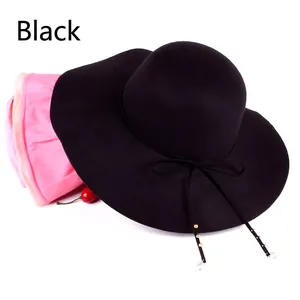 Detailed view of black wool wide brim fedora hat with bow and golden pearl beads