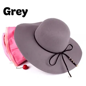 Detail of grey wide brim wool hat with pearl and ribbon bow on stack of pink and orange hats