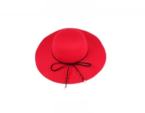 Detail of red wool felt hat featuring a black ribbon bow with gold and pearl accents