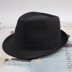 Gros plan d'un chapeau fedora noir à fines rayures posé sur des magazines de mode chic