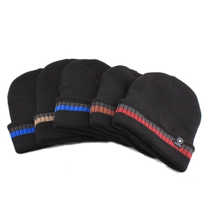Detail of five black knitted beanies with colorful stripes and sports star woven labels