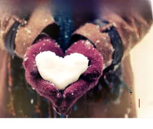 Detail of warm purple knitted gloves holding a heart-shaped snowball in winter