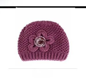 Detailed close-up of dark purple winter knit hat with a large crochet flower and pom-pom