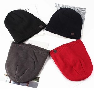 Flat lay of knit beanies in black, navy, grey, and red with leather patches on magazines