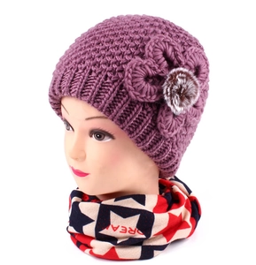 Detailed close-up of purple knit winter hat with handmade flower and matching scarf