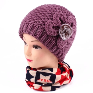 Close-up of thick knit purple winter hat with crochet flower and fur pompom detail