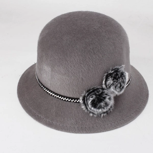Détail d'un chapeau cloche d'hiver gris en fausse fourrure avec pompons et ruban tissé