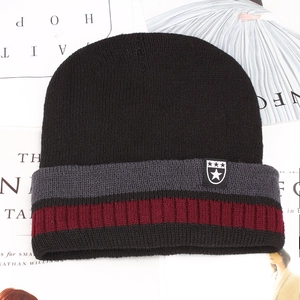 Detail of striped knitted beanie featuring shield star patch and thick ribbed texture