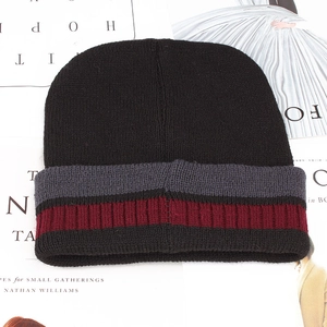 Detailed knit texture of a black winter beanie with grey and wine red striped cuff detail
