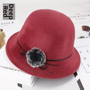 Détail d'un chapeau cloche en fausse fourrure rouge foncé avec pompon décoratif doux