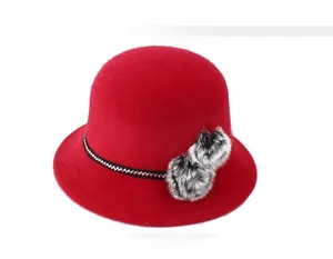 Détail du chapeau cloche rouge d'hiver avec ruban texturé et pompons en fourrure