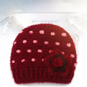 Detail of dark red thick knit winter hat with pink polka dots and floral accent