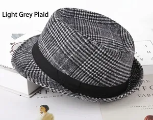 Close-up of light grey plaid fedora hat with black ribbon on minimalist book stack