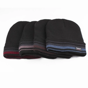 Flat lay of four knit beanies in red, grey, brown, and blue with striped turn-up cuffs