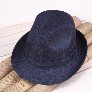 Detail of dark blue checkered fedora hat with metallic eyelets on vintage newspaper