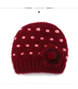 Detailed knit texture of burgundy winter hat with pink polka dots and side floral accent