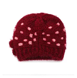 Detail view of the back of a deep red knit beanie with soft fuzzy texture and pink dots