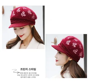 Detail of burgundy knitted rabbit fur newsboy hat with white leaf patterns and texture
