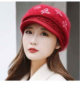 Detail of red knit winter hat featuring soft plush texture and elegant leaf embroidery