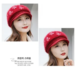 Detail of red winter knit hat featuring elegant white floral embroidery and fuzzy texture