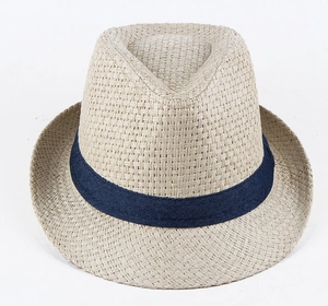 Close-up of woven straw fedora hat featuring a classic navy blue decorative ribbon band