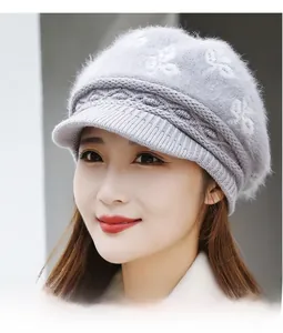 Close-up of light grey knit beanie with white floral patterns and soft fur texture