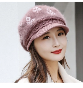 Detail of dusty pink knitted hat with visor and white floral pattern for winter