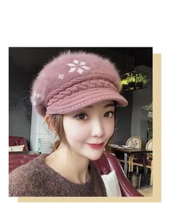 Close-up of pink fluffy winter cap with snowflake patterns and ribbed knit visor detail