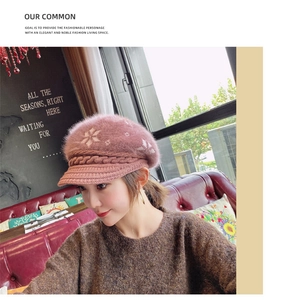 Detail view of a pink knit beret featuring snowflake patterns and plush fur texture
