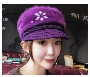 Close-up of deep purple knit hat with snowflake pattern and plush fur top detail
