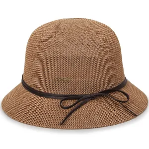 Detail of a brown woven sun hat featuring a round dome and a dark brown bow accent