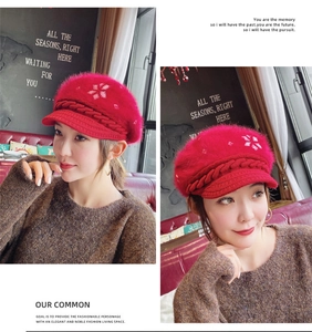 Detail of red cable knit beret with floral embroidery and fluffy faux fur texture