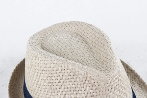 Detailed close-up of straw Fedora weave texture and navy blue ribbon accent on brim