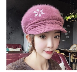 Close-up of pink knit winter hat featuring soft faux fur texture and white snowflake patterns