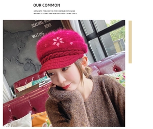 Rose red knitted newsboy hat with white snowflake embroidery in a cozy cafe setting