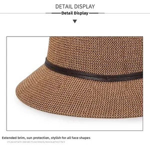 Detail of tan woven straw sun hat showing texture and thin brown leather decorative band
