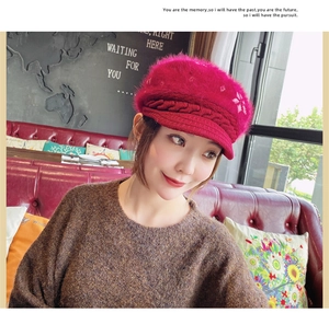 Detail of red cable knit newsboy hat with soft rabbit fur texture and snowflake embroidery