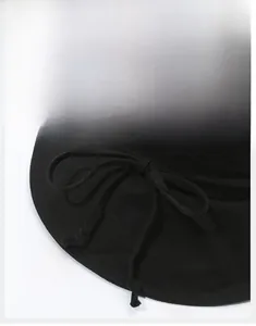 Detail of a black wide brim sun hat featuring a decorative fabric bow on the side