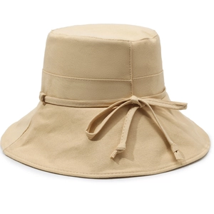 Detail of beige cotton sun hat featuring a decorative ribbon bow and canvas texture