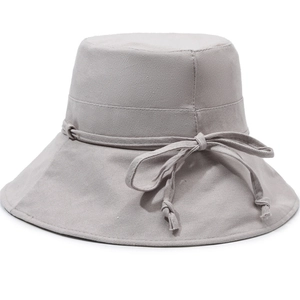 Women's foldable beige canvas bucket hat with elegant bow ribbon for sun protection