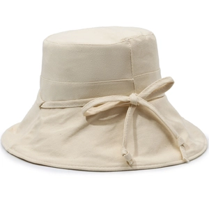 Detailed view of cream canvas bucket hat with elegant bow knot decoration on the side