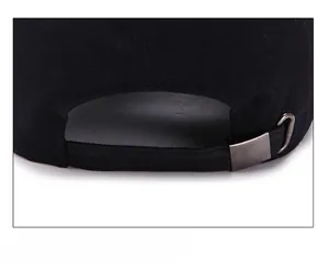 Detail of adjustable metal buckle and strap on back of black cotton baseball cap