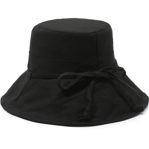 Detailed close-up of a black cotton sun hat featuring a side bow decoration on a white background